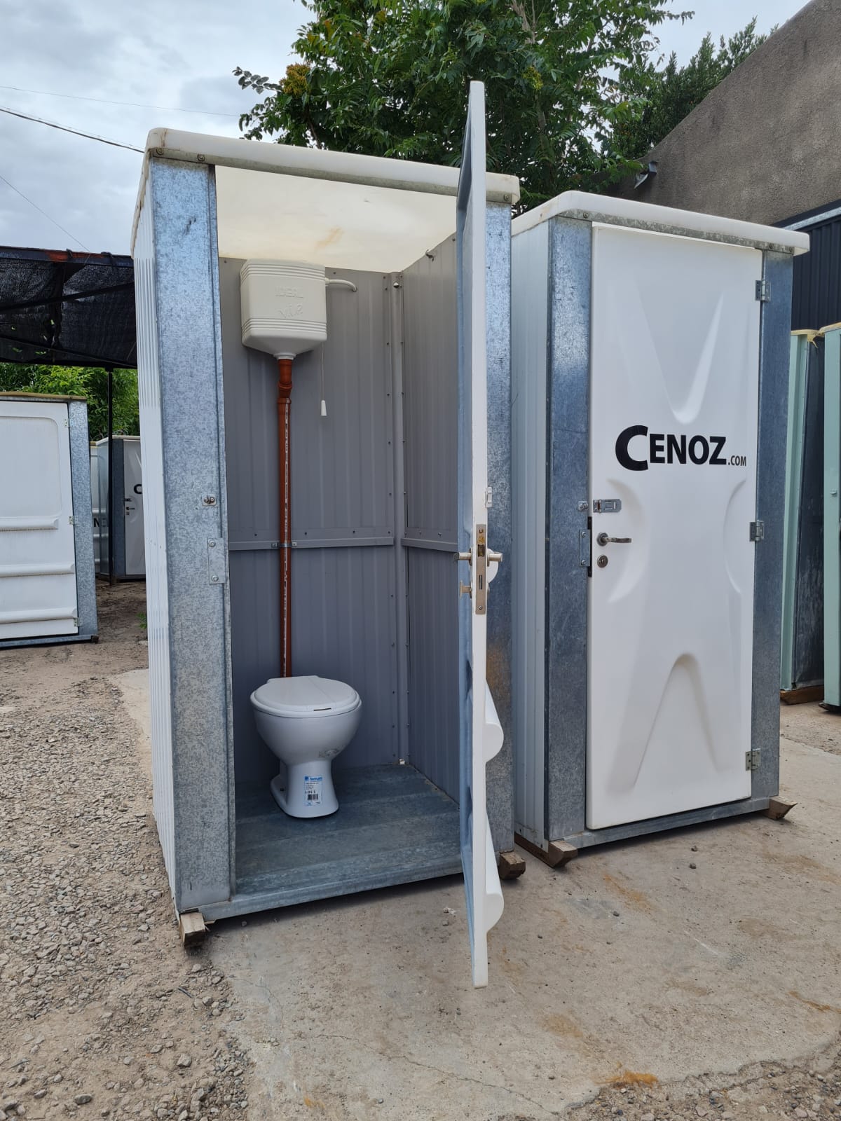 Baño químico cloacal blanco con puerta abierta y sanitario interior instalado