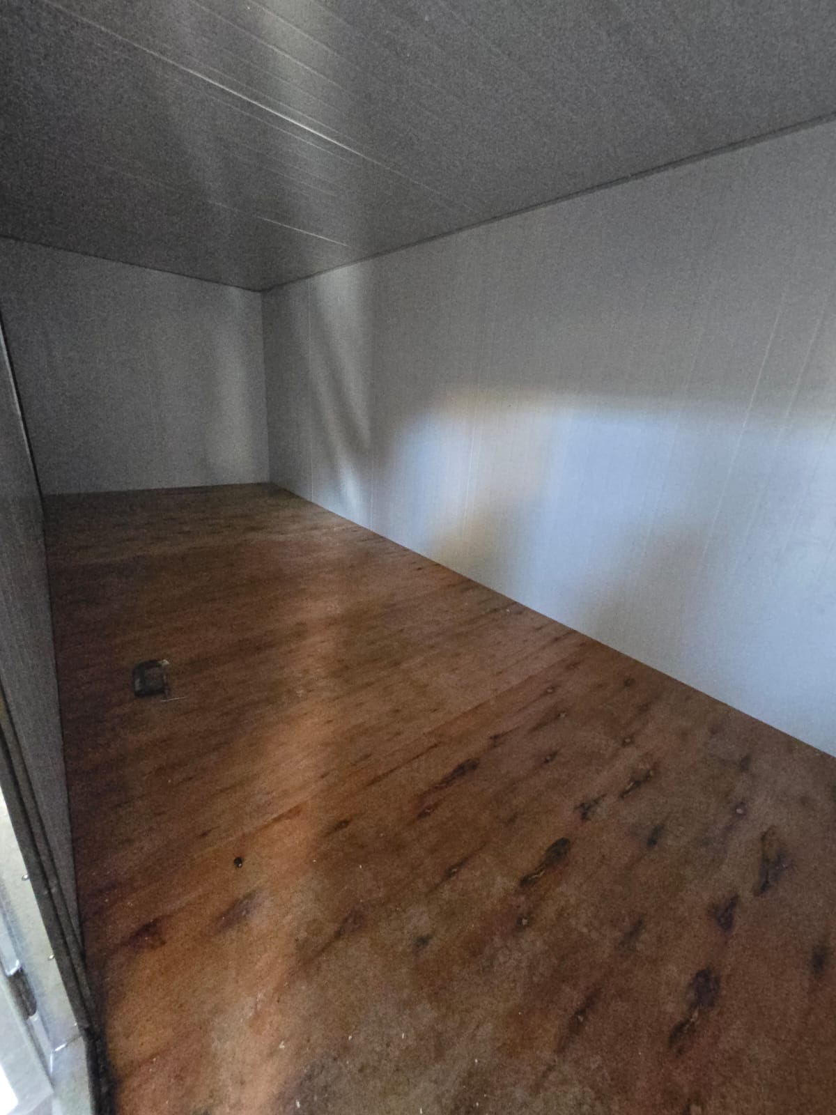 Interior de modulo portatil de paneles de 6 metros con piso de madera y paredes claras