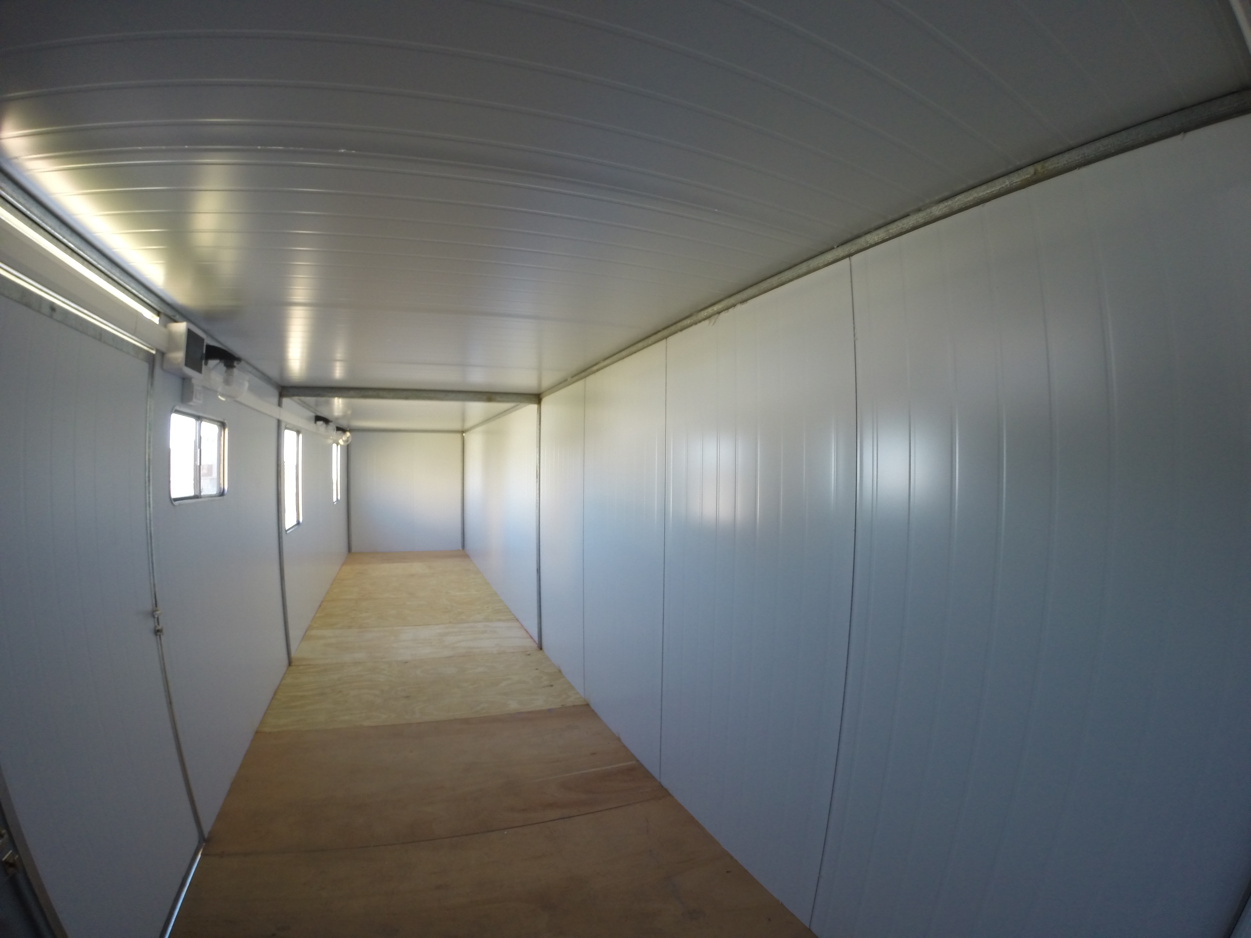 Interior de un trailer petrolero de paneles con revestimiento blanco y ventanas laterales